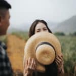 woman hides her smile with hat
