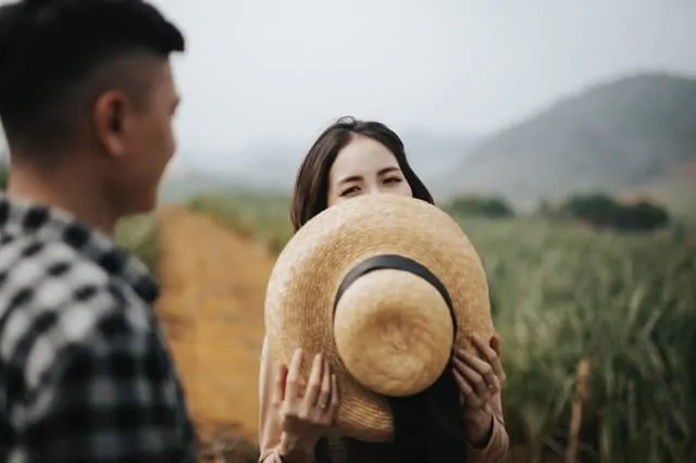 woman hides her smile with hat